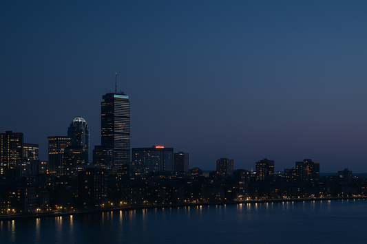 A nighttime aerial view of Boston with glowing city lights, representing the sleep deprivation crisis in Massachusetts.
